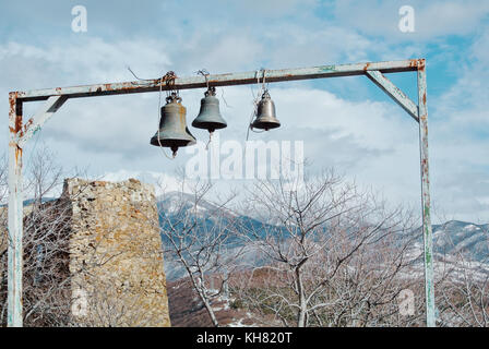 Drei Glocken und die Ruinen einer Mauer in der Nähe des dschuari orthodoxe Kloster in der Nähe von mzcheta, Ost Georgien, im Winter bewölkten Tag. mountaiins abgedeckt w Stockfoto