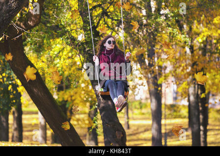 Junge entspannt erwachsenen Mädchen Schwingen auf einer Schaukel im Herbst Park in Vilnius, Litauen Stockfoto