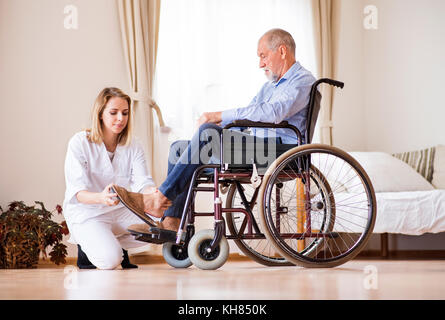 Krankenschwester und älterer Mann im Rollstuhl zu Hause besuchen. Stockfoto