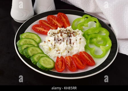 Einfaches Frühstück mit Paprika, Tomaten, Gurken mit Quark und Leinsamen auf einem Schild auf einem dunklen Hintergrund Gesunde Ernährung Gesunde Ernährung Konzept. Stockfoto