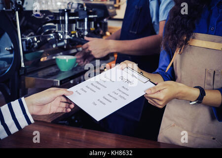 Baristas empfehlen Kaffee Menü zu Kunden. Cafe Restaurant Service, Inhaber kleiner Unternehmen, die Lebensmittel- und Getränkeindustrie. Stockfoto