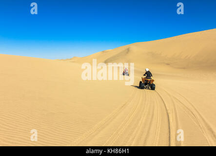 Quad fahren - zwei glückliche Biker im Sand der Wüste. Stockfoto