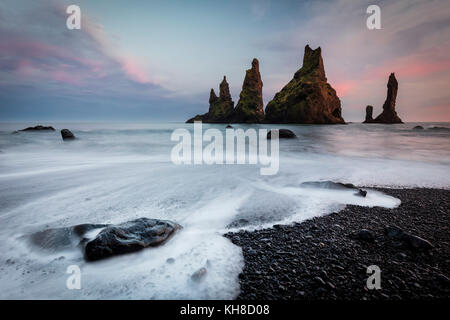 Felsformationen im Meer bei Sonnenuntergang, langfristige Exposition, schwarzen Strand, reynisdrangar, Vik, Island Stockfoto