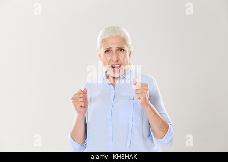 Foto der freudigen ältere Frau etwas Unterstützung, von der Kamera suchen, auf weißem Hintergrund Stockfoto