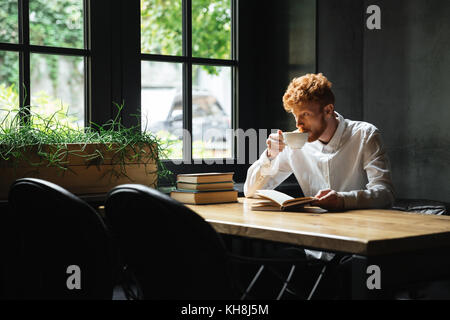 Foto von stattlichen Abtastkopf bärtiger Mann trinken Kaffee in City Cafe, großes Fenster Stockfoto