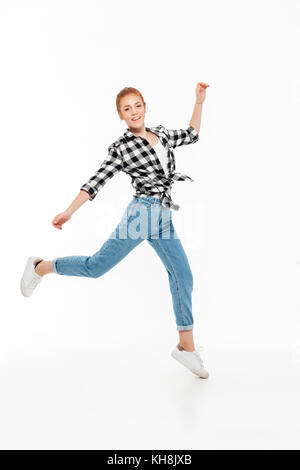 Volle Länge Bild der glücklichen Ingwer Frau in T-Shirt und Jeans laufen, und wenn man die Kamera auf weißem Hintergrund Stockfoto