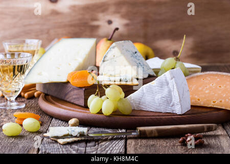 Käse, Obst und Wein Holz Schneidebrett, köstliche Vorspeise Urlaub auf rustikalen Tisch Hintergrund Stockfoto