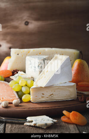 Käse, Obst und Wein Holz Schneidebrett, köstliche Vorspeise Urlaub auf rustikalen Tisch Hintergrund Stockfoto