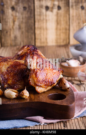 Gebratenes Hähnchen Schenkel mit Knoblauch auf rustikalen hölzernen Schneidebrett Stockfoto