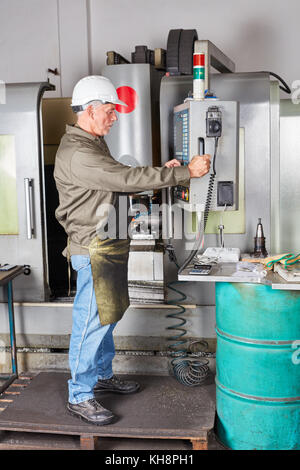 Arbeitnehmer mit CNC-Maschine in der Metallurgie Factory Stockfoto