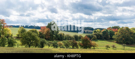 Anfang Herbst in einer Landschaft bei bewölktem Himmel. schöne bunte Panorama mit Bäumen im Sonnenlicht. Stockfoto