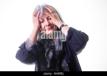 Eine grauhaarige ältere ältere, ältere Frau, die sich die Stirn reibt, an Kopfschmerzen oder Migräne leidet Stockfoto