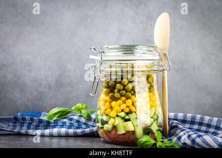 Gesunde hausgemachte Salate in ein Glas mit Gemüse, Gurken, Tomaten, Erbsen und Mais - gesunde Ernährung, Entgiftung, reine Nahrung oder vegetarische Konzept Stockfoto