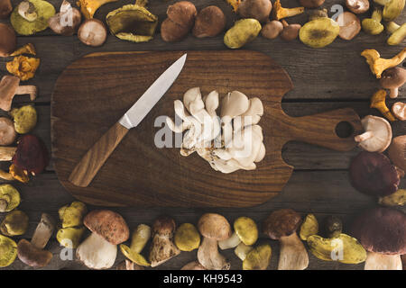 Austernpilze und Messer auf Schneidebrett Stockfoto