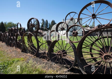 Alter Bauernhof Zaun von alten verrosteten Wagen & Räder des Schleppers an die Handwerker, die auf der dahmen Scheune ist auf der Palouse Scenic Byway in Uniontown, Washington, Stockfoto