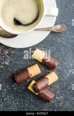 Süße Nachspeise. Kekse Brötchen mit Schokoladenglasur und Kaffee Tasse. Stockfoto