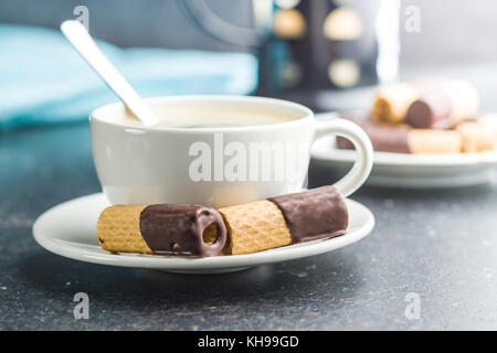 Süße Nachspeise. Kekse Brötchen mit Schokoladenglasur und Kaffee Tasse. Stockfoto