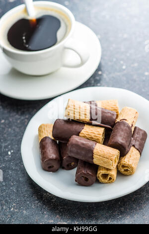 Süße Nachspeise. Kekse Brötchen mit Schokoladenglasur und Kaffee Tasse. Stockfoto