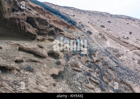 Vulkanischen Formationen in Montaña Amarilla Strand (Playa de La Cocina) in einem bewölkten Tag mit einer Frau im Hintergrund, La Graciosa, Kanarische Inseln, Spanien Stockfoto
