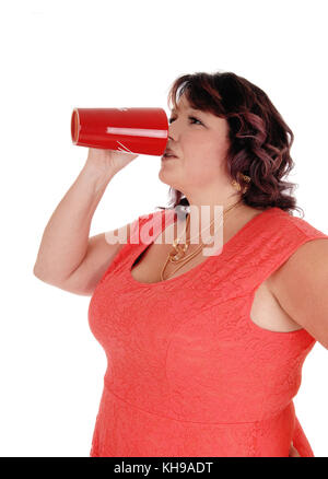 Eine übergewichtige Frau in rotem Kleid stehen im Profil mit einer Halskette und trinken Kaffee aus einem roten Becher, auf weißem Hintergrund Stockfoto