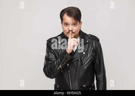Bärtiger Mann mit Schnurrbart, shh unterzeichnen und Kamera. studio Shot, grauer Hintergrund Stockfoto