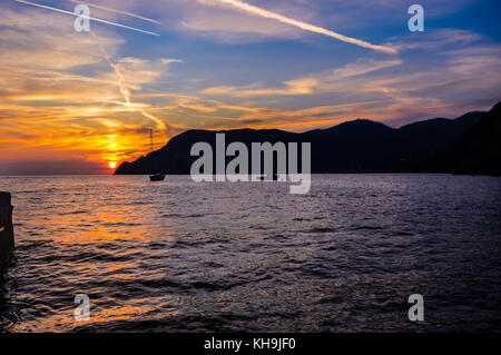 Boote in der schönen Bucht von Vernazza im Ligurischen Region Cinque Terra an der nördlichen Küste von Italien, wie die Sonne hinter einem Berg Stockfoto