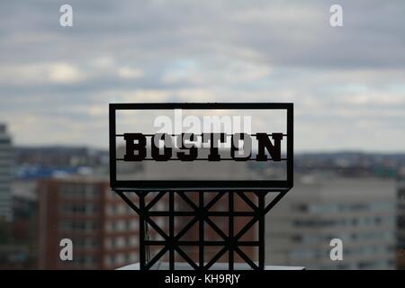 Ein "Boston" billboard Zeichen Makroaufnahme mit dem Boston Stadtbild dahinter mit der Ikonischen zakim Brücke und die Boston Skyline Stockfoto