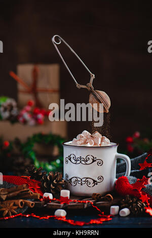 Heiße Schokolade mit Marshmallows und fliegende Kakaopulver in Weihnachten Szene mit Geschenken. Aktionsfotografie mit fliegenden Sieb Stockfoto