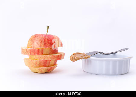 Einen Apfel in Schichten übereinander gestapelt und ein Messer mit Peanut Butter in eine Schüssel geben. Stockfoto