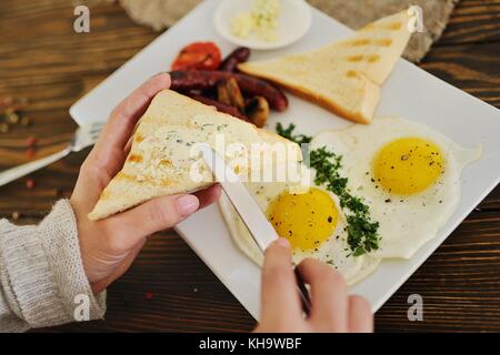 Hand mit einem Messer schmiert Butter auf Brot close-up auf einem Frühstück Hintergrund Stockfoto