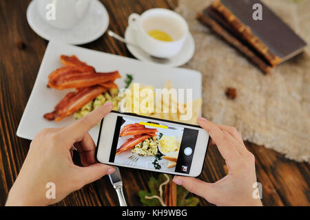 Mädchen nimmt das Frühstück auf der Kamera smartphone Stockfoto