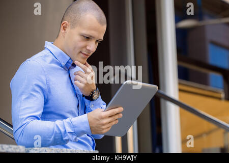 Hübscher junger Mann mit Tablet mit Gebäude Hintergrund Stockfoto