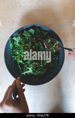 Organic Baby kale Salat mit Mit glutenfreie Semmelbrösel in eine blaue Keramik Schüssel geworfen. Stockfoto