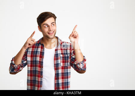 Nahaufnahme von Happy attraktiven jungen Mann in kariertem Hemd zeigte mit zwei Fingern, abgesehen suchen, auf weißem Hintergrund Stockfoto