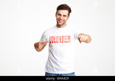 Portrait Of Happy fröhlicher Mann, der Freiwilligen-T-Shirt zeigen Sie mit zwei Fingern auf weißem Hintergrund Stockfoto