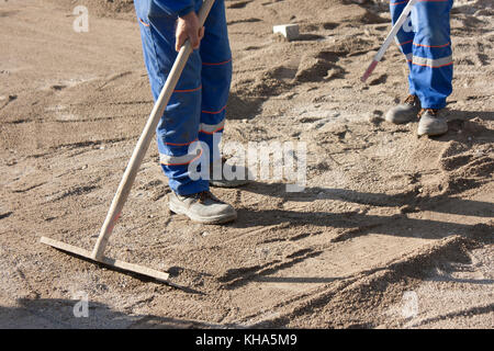 Baustelle: Straße pflastern Vorbereitung, zwei Arbeiter Abflachung der Sand base Stockfoto