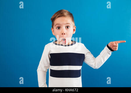 Schockiert Junge in Pullover weg zeigen, und wenn man die Kamera über blauer Hintergrund Stockfoto