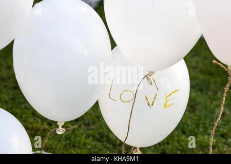 Weiße Ballons über Gras sagt 'Liebe' bei einer Hochzeit. Vintage Dekoration für Hochzeiten Stockfoto