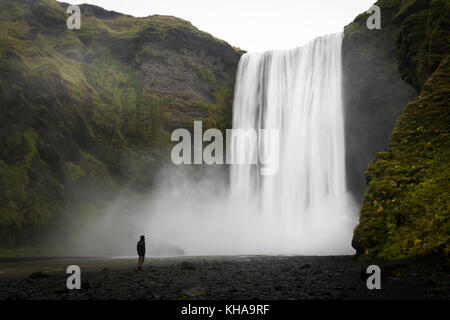 Person vor Wasserfall Skogafoss, Langzeitbelichtung, Skogar, Island Stockfoto