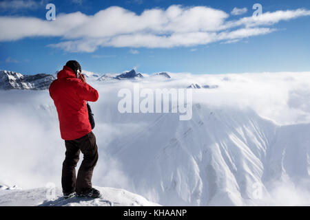 Skifahrer an der Oberseite des Gespräch am Handy und Schnee Berge in Nebel montieren. Kaukasus, die in der Sun Wintertag, Georgien, Region Gudauri. Stockfoto