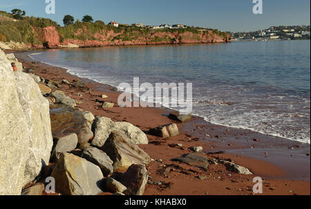 Rock Rüstung auf Hollicombe Beach - große Felsbrocken gegen roten Sandsteinfelsen angehäuft weitere Erosion durch das Meer zu verhindern. Stockfoto