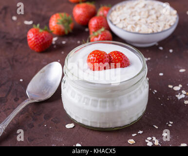 Weißer Joghurt im Glas Schale mit Löffel und starwberries auf rustikalen Hintergrund. Stockfoto