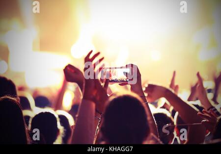 Fans Aufnehmen von Bildern und Aufnehmen von Filmen mit Smartphones während des Live Konzert einer Rockband auf der Bühne mit Vintage-effekt Stockfoto