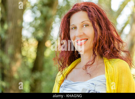 Porträt des Deutschen reife Frau mit gelbem Schal und Silber top in einem grünen Garten lächeln Stockfoto