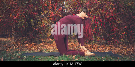 Mädchen an einem strahlenden Herbsttag Üben Yoga im Freien, Kamel darstellen (ustrasana) Stockfoto