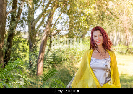 Porträt des Deutschen reife Frau mit gelbem Schal und Silber top in einem grünen Garten lächeln Stockfoto