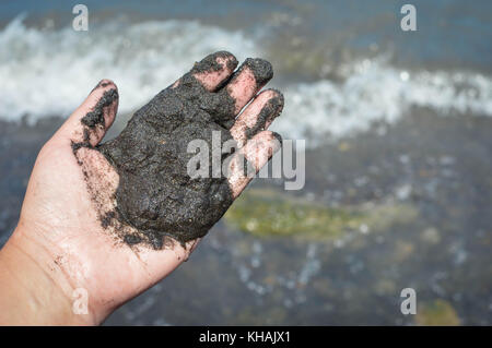 Die hand hält schwarzen vulkanischen Sand am Strand der vulkanischen Kratersee Laguna de Apoyo im Hochland in der Nähe von Masaya, Nicaragua. Mittelamerika Stockfoto