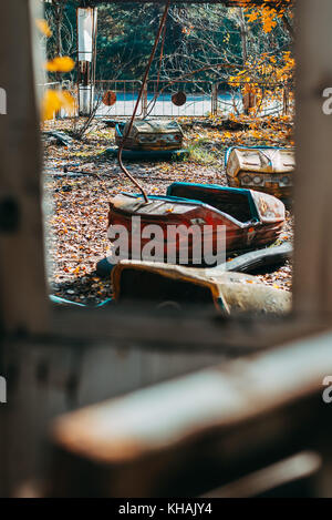 Beim Blick durch ein Fenster an einem alten Stoßstange car im Herbst Blätter in der berüchtigten verlassenen Freizeitpark liegt in Pripyat, in der Nähe von Tschernobyl, Ukraine Stockfoto