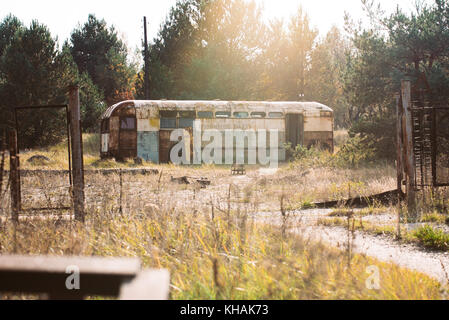 Eine verlassene, heruntergekommen Bus liegt in einem leeren Bereich der langen Gras im Herbst Nachmittag Sonne in Pripyat, Ukraine Stockfoto