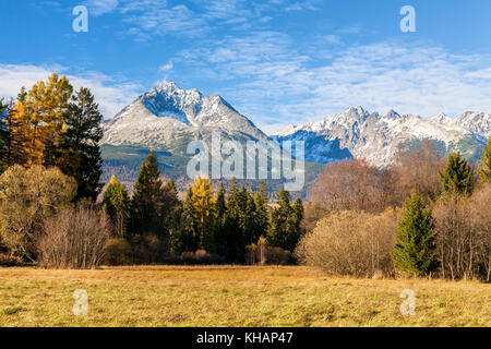 Hohe Tatra mit wenig Schnee im Gegensatz zu den Farben der Bäume im Herbst, Slowakei bedeckt. Stockfoto